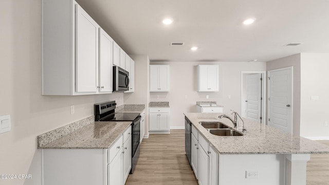 kitchen featuring a center island with sink, recessed lighting, a sink, stainless steel appliances, and light wood-type flooring