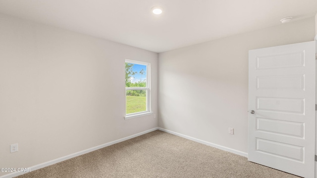 spare room with light carpet and baseboards