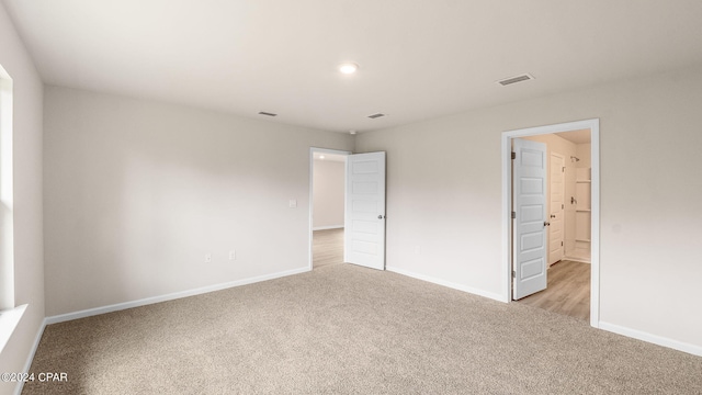 unfurnished bedroom with visible vents, light colored carpet, and baseboards