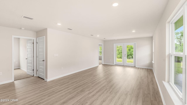 unfurnished room featuring a wealth of natural light, visible vents, and light wood-type flooring