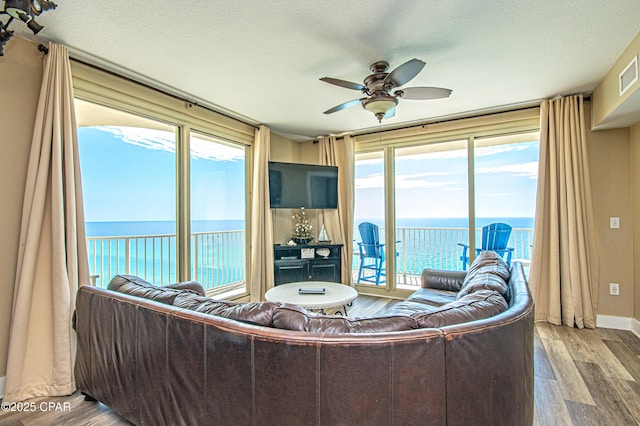 living room with a ceiling fan, visible vents, a textured ceiling, and wood finished floors