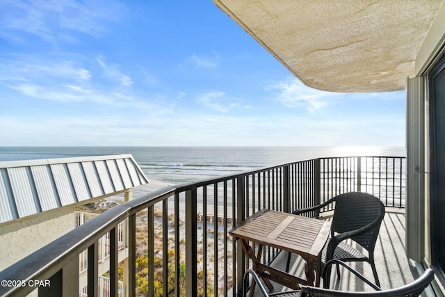 balcony with a water view and a view of the beach