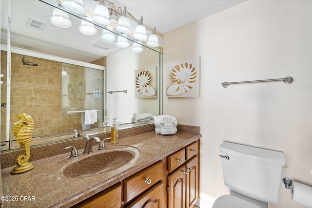 bathroom featuring toilet, a stall shower, visible vents, and vanity