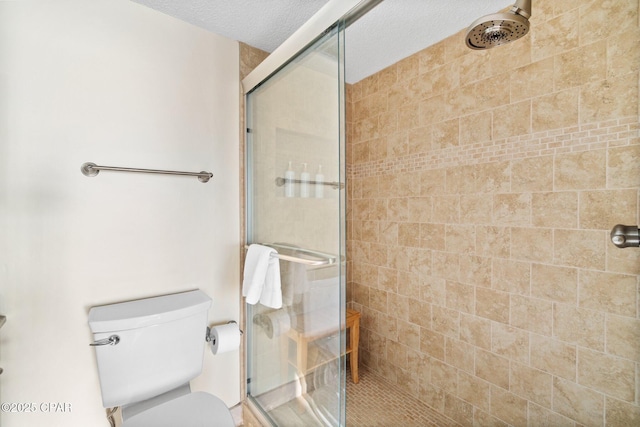 bathroom with toilet, a shower stall, and a textured ceiling