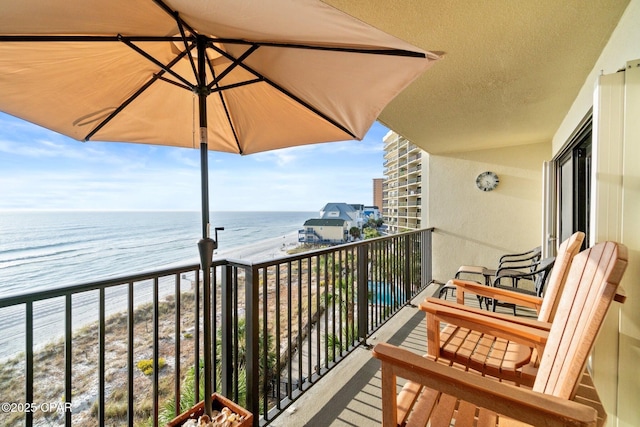 balcony with a water view and a view of the beach