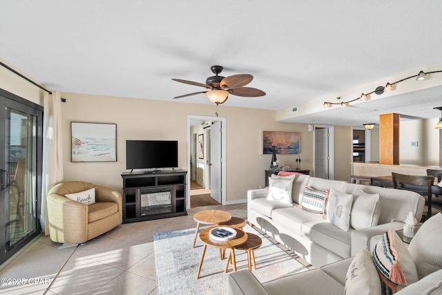 living room featuring ceiling fan, light tile patterned flooring, a fireplace, and visible vents