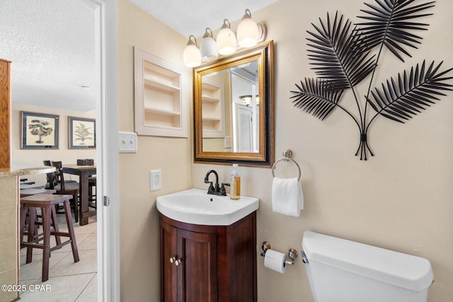 half bath with vanity, a textured ceiling, toilet, and tile patterned floors