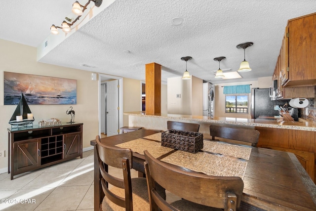 dining room featuring light tile patterned floors, baseboards, visible vents, and a textured ceiling