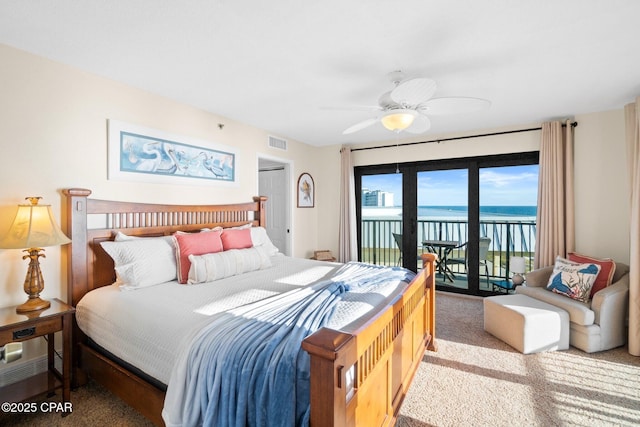 carpeted bedroom featuring access to outside, a water view, visible vents, and a ceiling fan