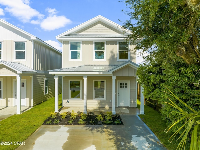 view of front of home featuring board and batten siding, covered porch, metal roof, and a front lawn