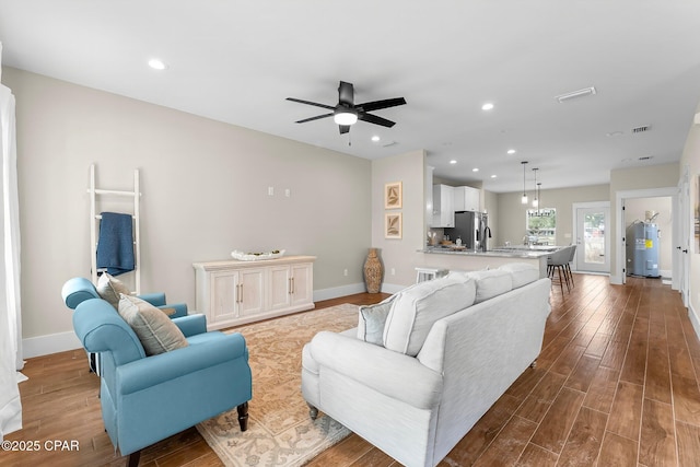 living area with light wood-type flooring, visible vents, baseboards, and recessed lighting