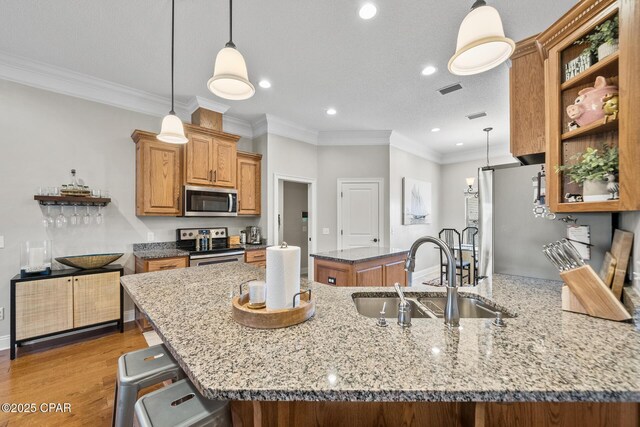 kitchen with decorative light fixtures, stainless steel appliances, light stone counters, and sink