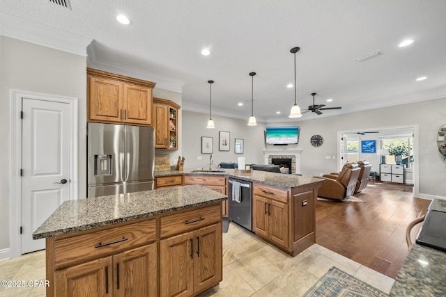 kitchen with light stone counters, a center island, decorative light fixtures, stainless steel appliances, and a fireplace