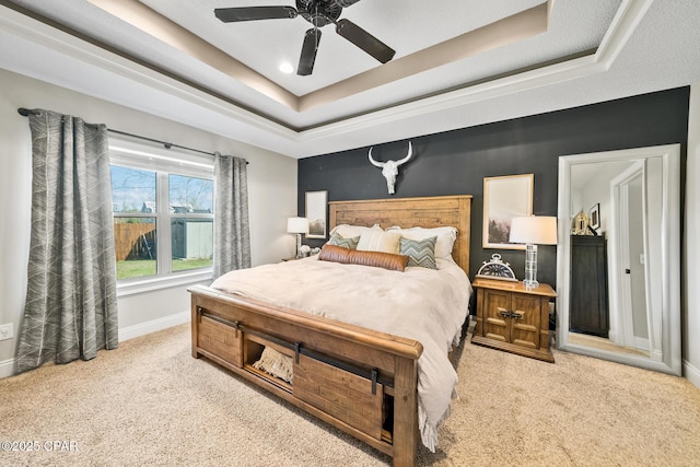 carpeted bedroom featuring a tray ceiling and ceiling fan