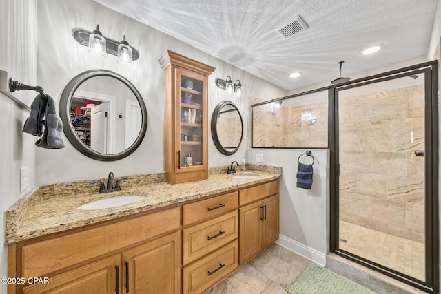 bathroom with vanity, a textured ceiling, and walk in shower