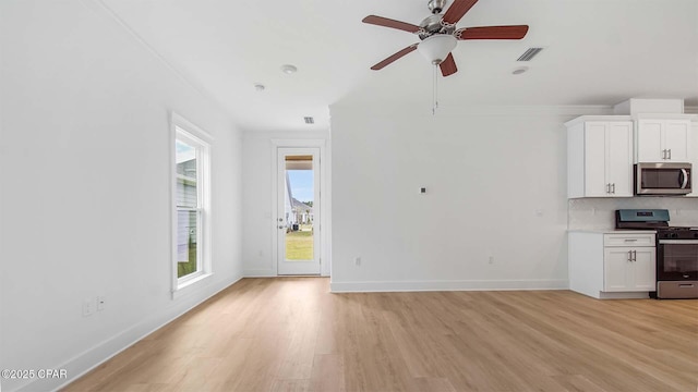 interior space featuring a ceiling fan, light wood-style floors, visible vents, and baseboards