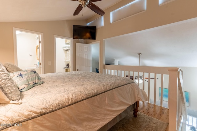 bedroom featuring a ceiling fan, vaulted ceiling, ensuite bath, and wood finished floors