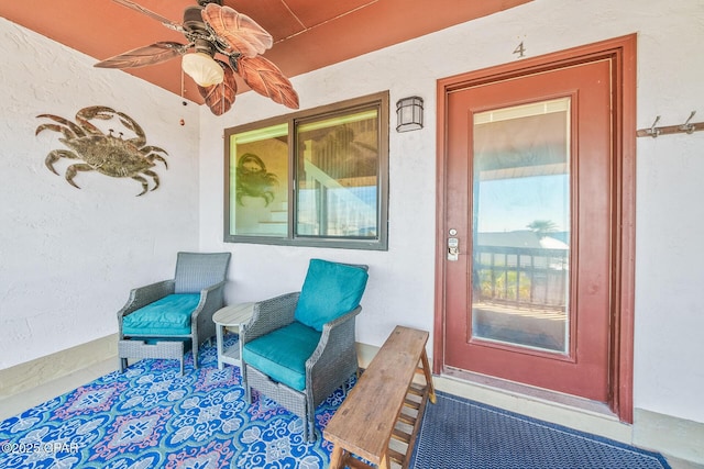 entrance to property featuring a ceiling fan and stucco siding