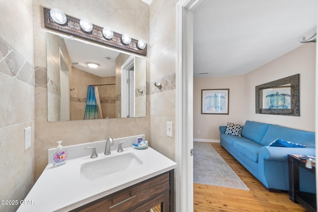 bathroom featuring tile walls, curtained shower, connected bathroom, vanity, and wood finished floors