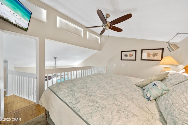 bedroom with a ceiling fan, vaulted ceiling, and wood finished floors