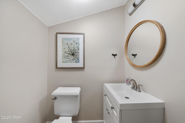 bathroom with lofted ceiling, toilet, a textured ceiling, and vanity