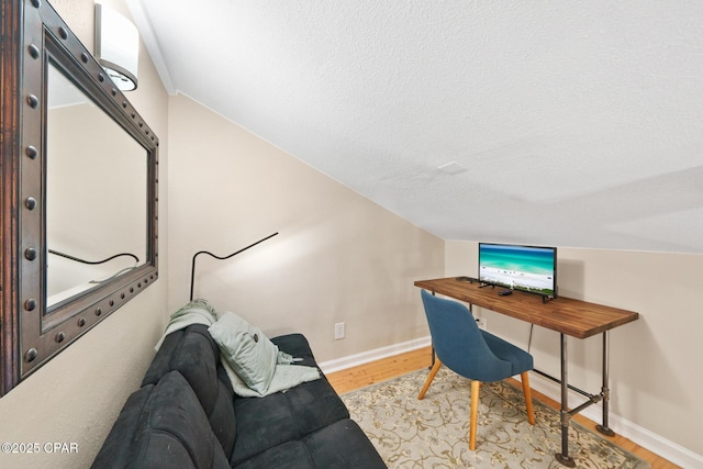 home office featuring light wood-type flooring, baseboards, and a textured ceiling