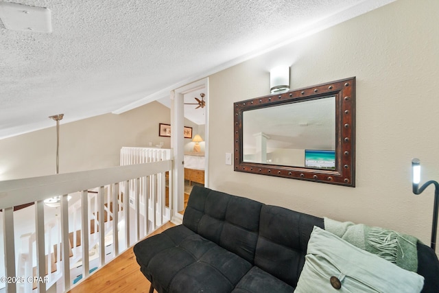 living room with a textured ceiling, vaulted ceiling, wood finished floors, and a ceiling fan