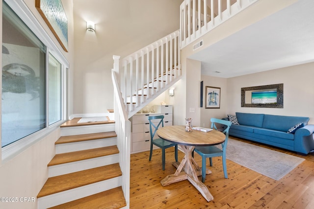 interior space with wood finished floors, visible vents, a high ceiling, and stairs