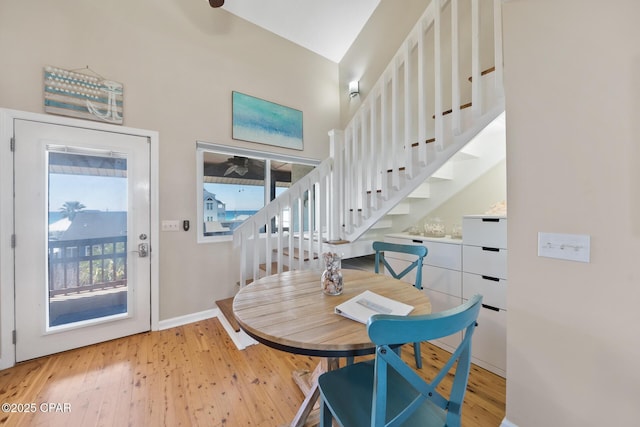 interior space featuring light wood-type flooring, baseboards, stairs, and a high ceiling