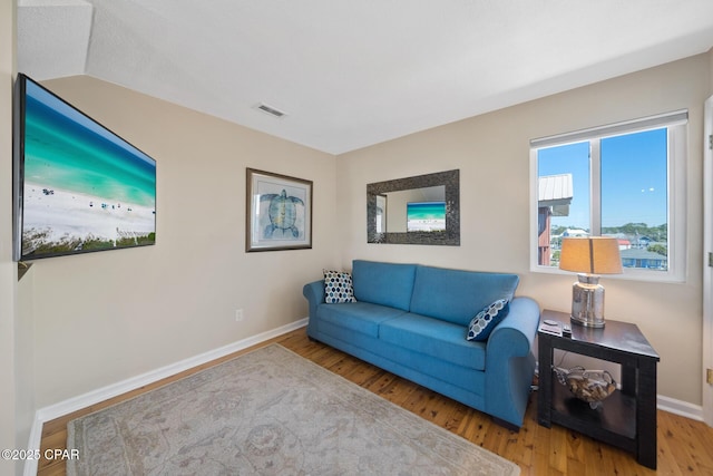 living area with baseboards, visible vents, and wood finished floors