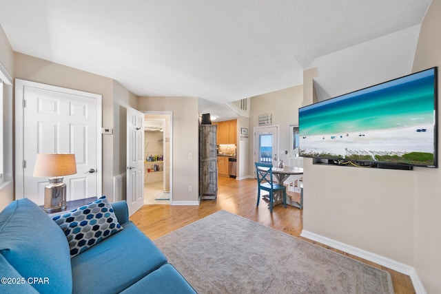 living room with light wood-type flooring, visible vents, and baseboards