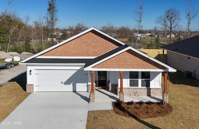 view of front of home with a garage, a front lawn, central AC, and a porch