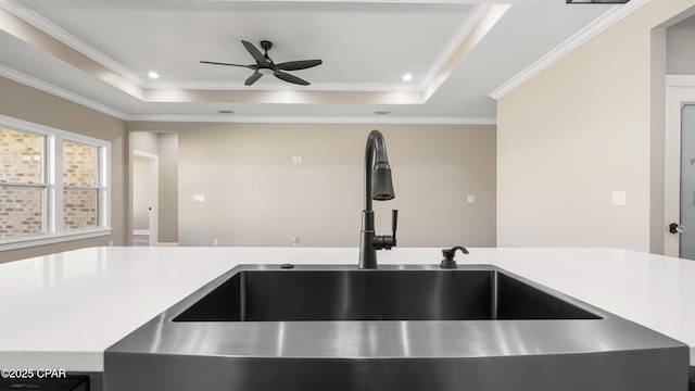 kitchen featuring a raised ceiling, ceiling fan, sink, and ornamental molding