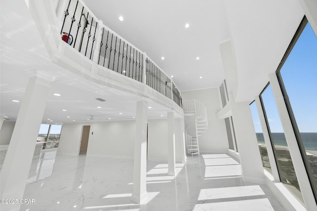 staircase featuring recessed lighting, a high ceiling, a water view, baseboards, and marble finish floor