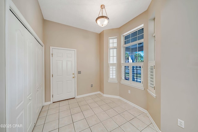 entrance foyer with plenty of natural light, baseboards, and light tile patterned flooring