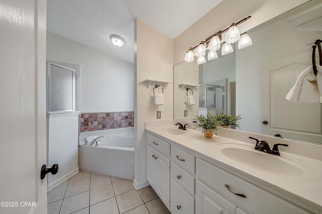 full bathroom featuring a bath, tile patterned flooring, a textured ceiling, and a sink