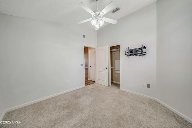 unfurnished bedroom featuring a textured ceiling, a ceiling fan, visible vents, baseboards, and carpet