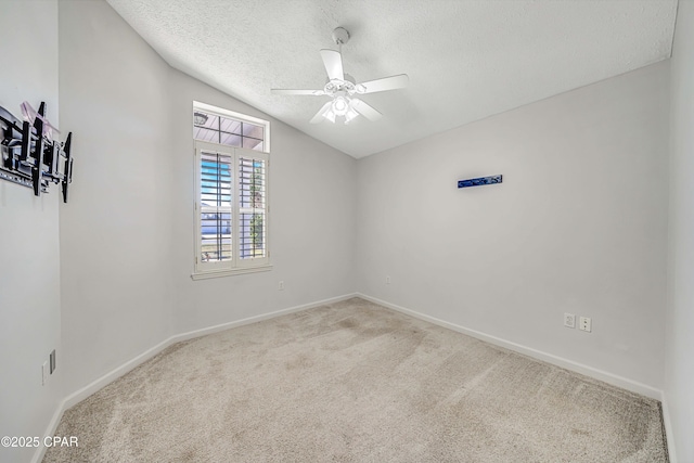 unfurnished room featuring lofted ceiling, ceiling fan, a textured ceiling, light colored carpet, and baseboards