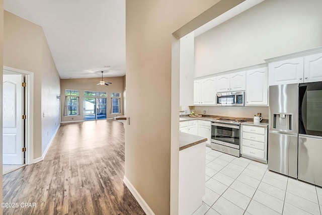 kitchen featuring appliances with stainless steel finishes, white cabinetry, high vaulted ceiling, and baseboards