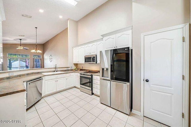 kitchen with white cabinets, dark countertops, appliances with stainless steel finishes, pendant lighting, and a sink