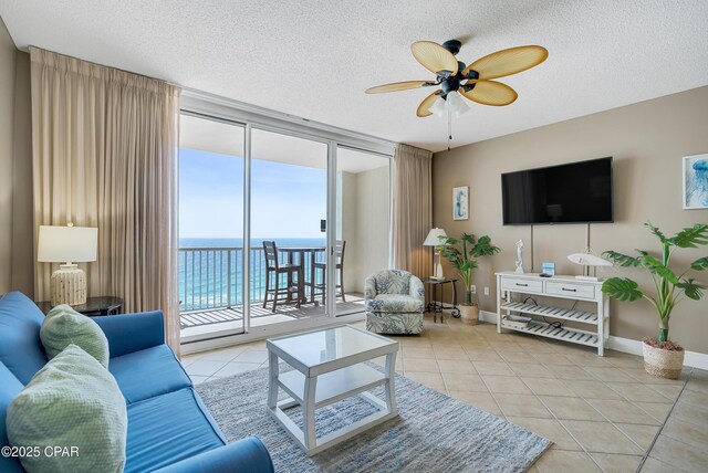 tiled living area featuring floor to ceiling windows, a textured ceiling, baseboards, and a ceiling fan