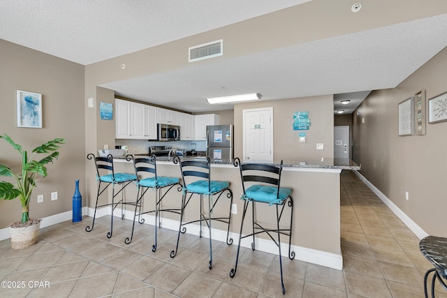 kitchen with visible vents, a peninsula, stainless steel appliances, and a kitchen breakfast bar