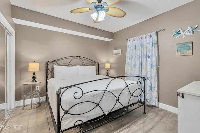 bedroom with tile patterned flooring, ceiling fan, a closet, and baseboards