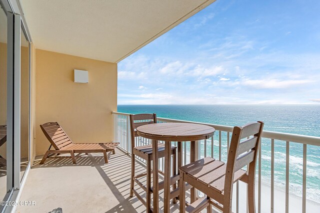 balcony featuring a view of the beach and a water view