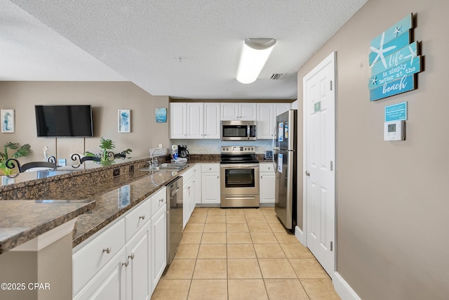 kitchen featuring visible vents, light tile patterned flooring, a sink, appliances with stainless steel finishes, and white cabinetry