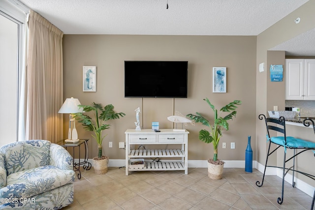 living area with light tile patterned flooring, baseboards, and a textured ceiling