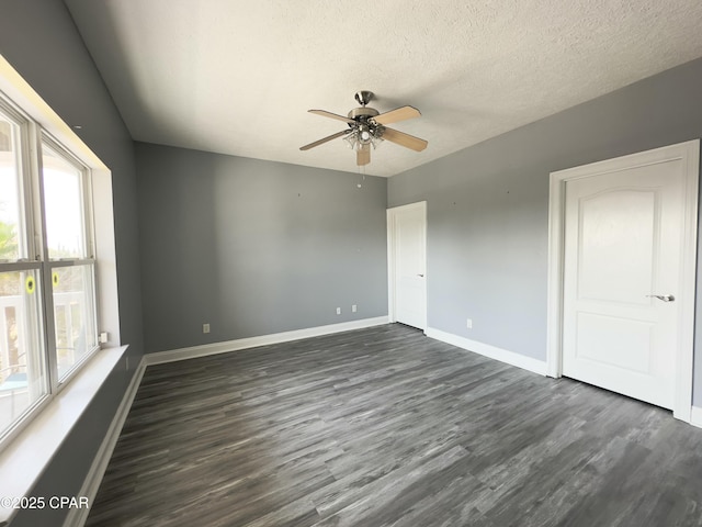 spare room featuring dark wood finished floors, a textured ceiling, baseboards, and ceiling fan