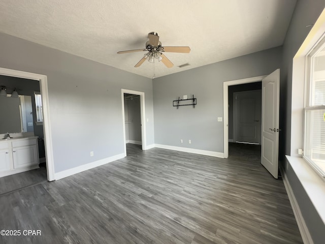 unfurnished bedroom with visible vents, baseboards, dark wood finished floors, and a textured ceiling