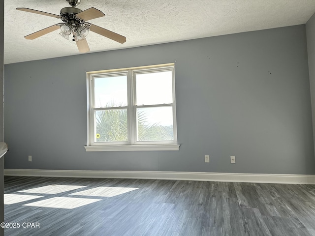 empty room featuring dark wood-type flooring, a textured ceiling, and baseboards