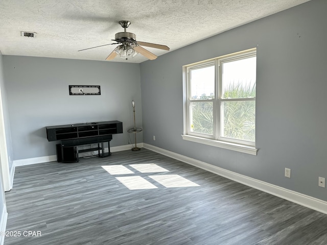 unfurnished room featuring dark wood-style floors, a textured ceiling, visible vents, and baseboards